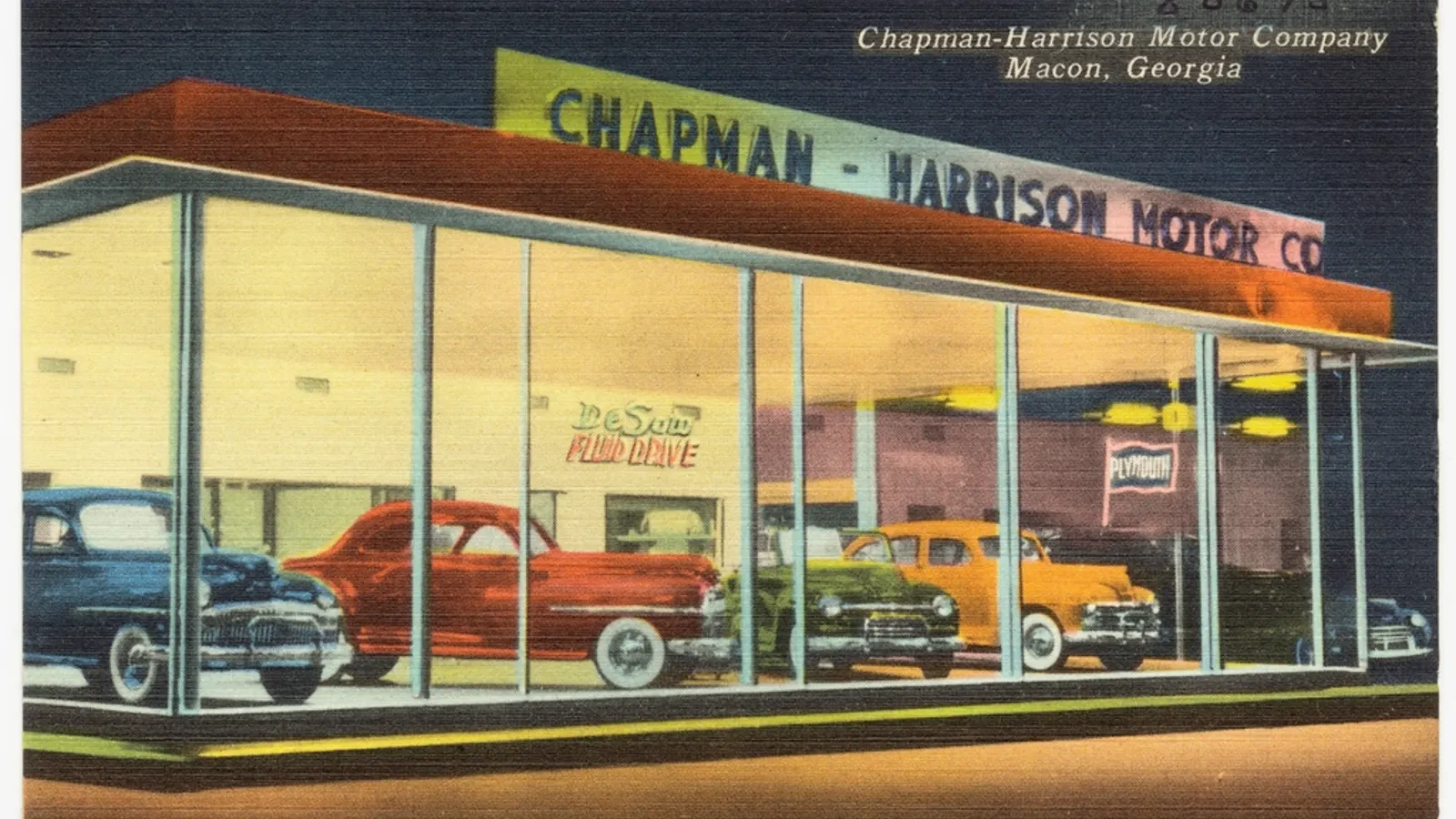 A car dealership showroom with a sales manager's desk overlooking new vehicles on the floor.