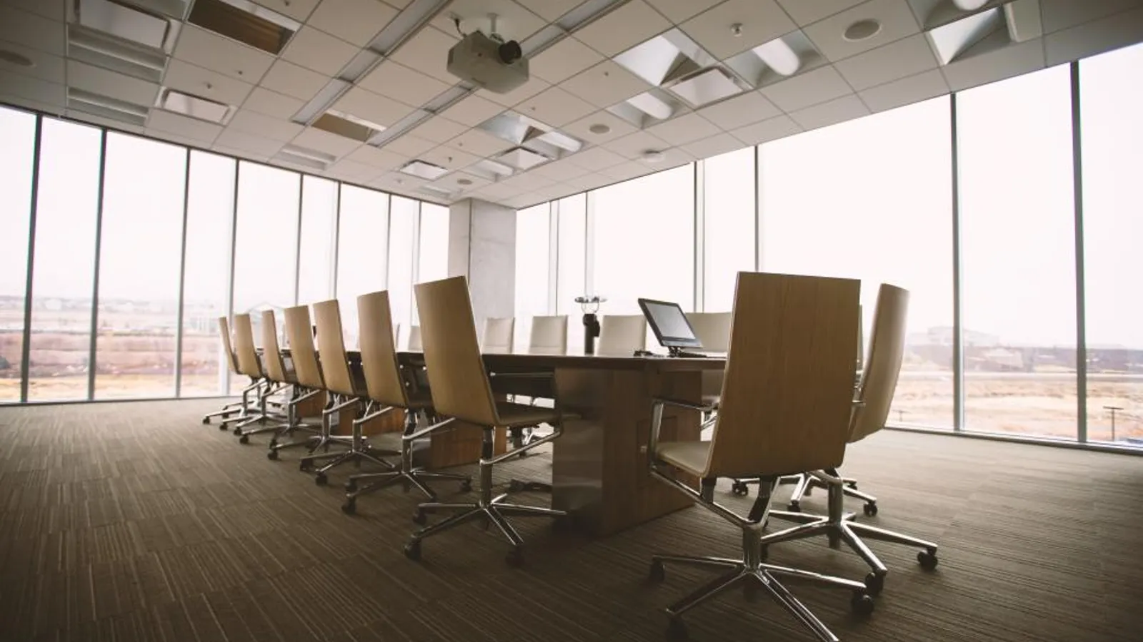 A salesperson presenting slides on a screen to three people around a conference room table.