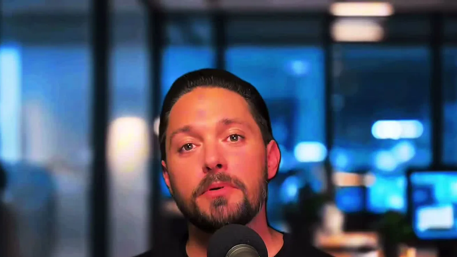 Greg Pahel of Clever Closers speaking into a podcast microphone in a dim office while teaching sales psychology.